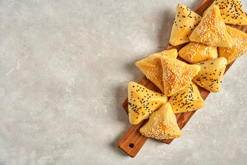Fatayer samosa with white cheese and black sesame seeds on wooden board.