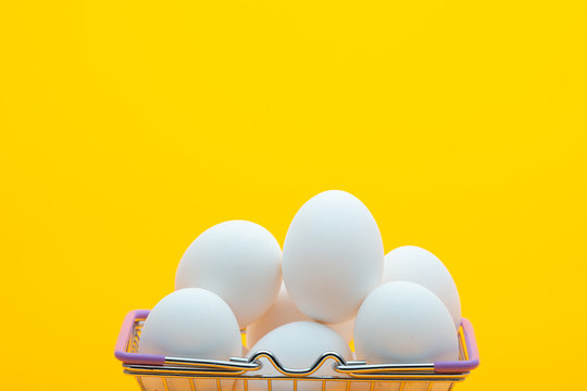 Chicken eggs are in the grocery basket, bright orange background