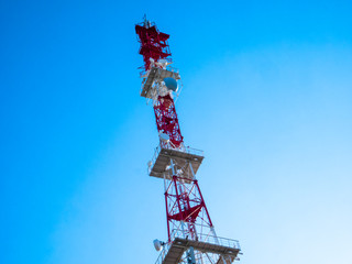 Television antenna metal tower against the blue sky on sunny day. Transmission cellular communication by wireless.