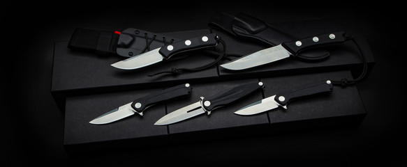 A variety of knives, penknife and hunting on a dark back. Modern knives with shiny blades.