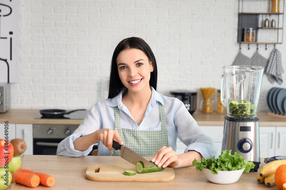 Sticker young woman making vegetable smoothie in kitchen at home