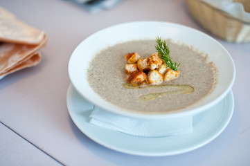 Cream soup with mushrooms champignon and potato in white bowl. Shallow depth of field.