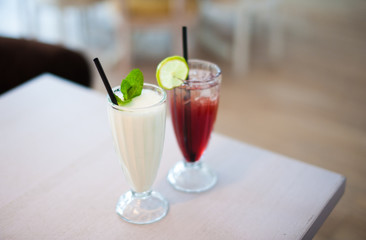 Two glasses of fresh lemonade or cocktails with ice on table in summer cafe. Shallow depth of field.