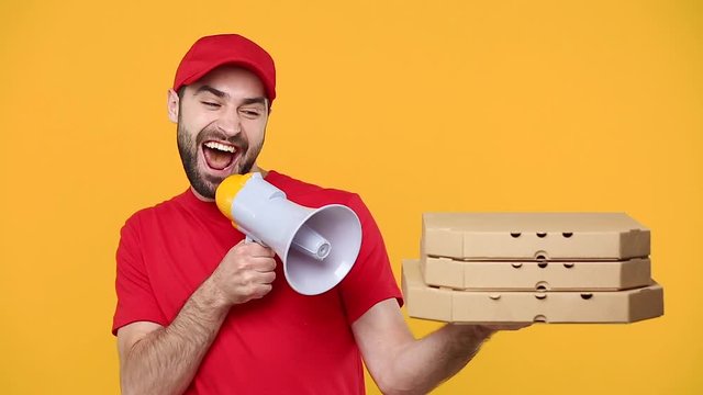 Delivery fun guy man in red cap t-shirt uniform workwear hold order pizza box takeaway scream in megaphone isolated on yellow background studio Professional male employee work courier Service concept