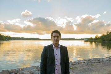 Fototapeta premium Young handsome businessman in front of beautiful scenic shore
