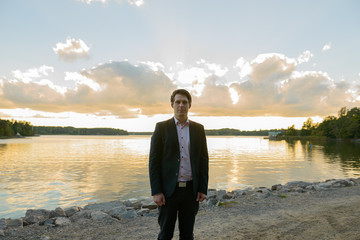 Fototapeta premium Young handsome businessman in front of beautiful scenic shore