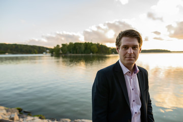 Fototapeta premium Young handsome businessman in front of beautiful scenic shore