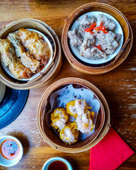 Top View of Delicious Chinese Dim Sum in Bamboo Steamer with Chili Oil and Soy Sauce.