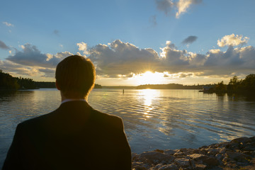 Back view of young businessman looking towards beautiful scenic shore