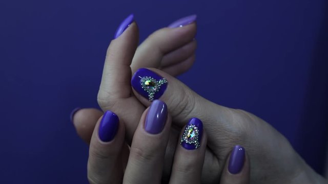 purple Fingers nail point isolated blue background with nail polish. Nail art manicure with cristals