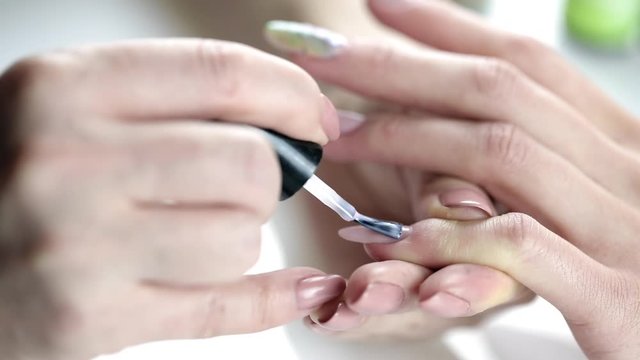 Application of nail polish on nails. Woman applying nude nail polish. manicure process