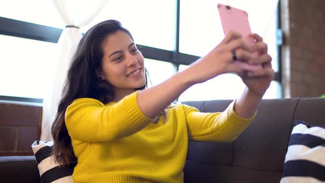 Beautiful teenager takes selfie with her smartphone, girl with colored eyes takes a picture for social networks.