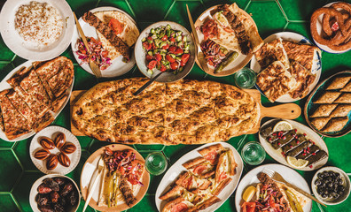 Muslim Ramadan iftar family dinner arrangement. Flat-lay of Middle East table with dates, dolma, kebab, flatbread, pide, borek, sweets, salad, top view, copy space. Ramazan fasting Turkish cuisine - 346658600