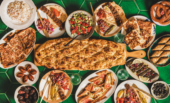 Muslim Ramadan iftar family dinner arrangement. Flat-lay of Middle East table with dates, dolma, kebab, flatbread, pide, borek, sweets, salad, top view, copy space. Ramazan fasting Turkish cuisine