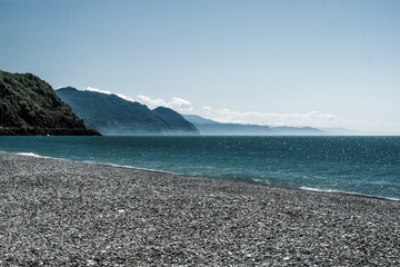 Mountain view from the beach. Sea coast made of pebbles. Ripples on the Black Sea. Spring, sunny...