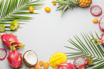 Frame made of different exotic fruits on grey background