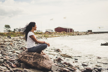 woman meditating and doing yoga on a rock