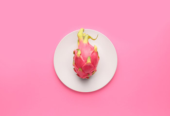 Tasty dragon fruit with plate on color background