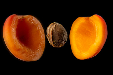 melocoton partido a la mitad, con semilla a la mitad, sobre fondo negro