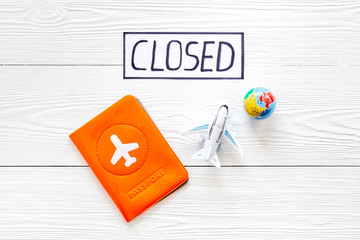Closed counrty borders - coronovirus quarantine. Airplane and passport on white wooden background...