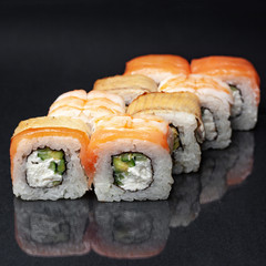 diverse delicious sushi roll set on a black background with reflection, menu