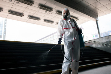 disinfection of the city from viruses and infections. sanitary worker in a protective suit and a respirator cleans the city with a chemical agent