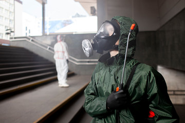 portrait of a disinfection service worker in a protective suit and a respirator against a city background, a sanitary worker