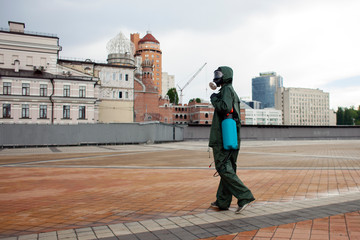 disinfection of the city from viruses and infections. sanitary worker in a protective suit and a respirator cleans the city with a chemical agent