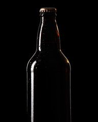 botella de cerveza con pocas gotas de condensaci&oacute;n, iluminado de contorno , sobre fondo negro