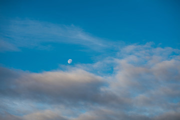 Detail of beautiful waxing gibbous moon and beautiful blue sky and some scattered clouds