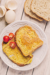 French toast, fried in eggs, lies in a plate on a light wooden rustic table. tinted beige
