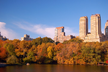 Fall foliage surrounds a lake in Central Park, with the skyline of the Upper West Side rising behind it