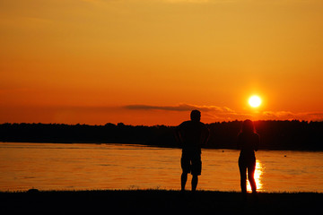 A couple watches the sun set over the horizon