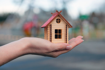 Close-up of hand holding wooden house model against blur background