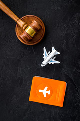 Flight cancellation. Airplane, passport, judge gavel on black desk top-down