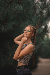 portrait of young prity confident woman against background of summer green park.