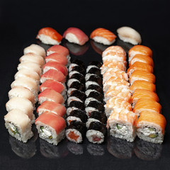 diverse delicious sushi roll set on a black background with reflection, menu