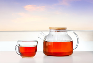 Morning Tea. Cup and teapot with tea on the table with sun near window.