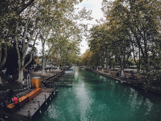 Fototapeta na wymiar Vassé canal and its moored boats, banks and lines of plane trees in autumn. Canal du Vasse as seen from Pont des Amours. Located in the Auvergne-Rhône-Alpes region, France.