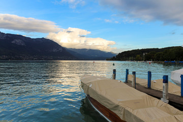 Bank of the Europe gardens, moored boats, Annecy lake and mountains mountain of La Tournette and the sharp rocky ridges of the Dents de Lanfon, Annecy, France.