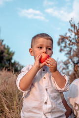 Boy in white shirt eats apple