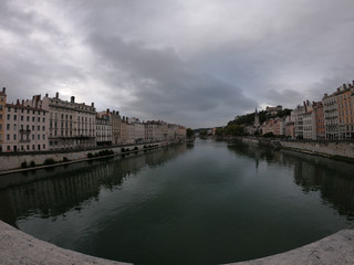Fototapeta premium Heading into Vieux Lyon over the Pont Bonaparte. Quai Tilsitt and Quai Fulchiron on the banks of the Saone river, Passerelle, Saint Georges church and Saint-Just College on Fourviere hill, Lyon.