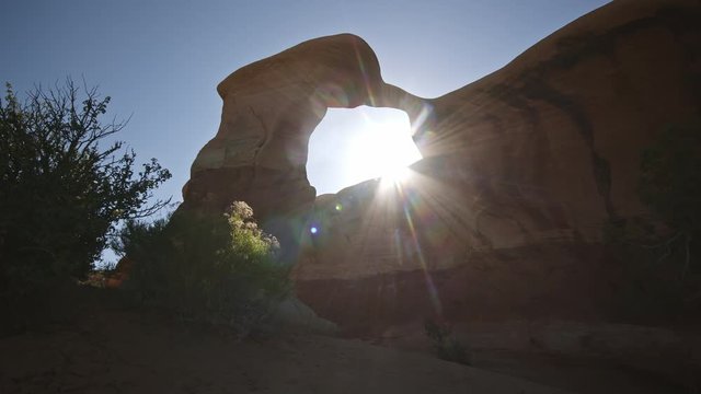 Sun shining through Metate Arch in Escalante while hiking in the desert.