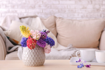 Vase with beautiful hyacinth flowers on table in room