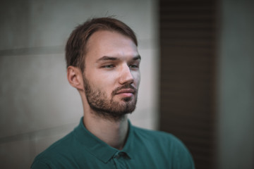 Fototapeta premium bearded man in blue T-shirt against the background of a white building