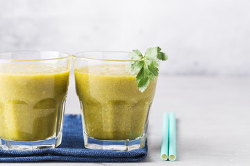 Green smoothies in glass with parsley leaf on denim napkin, gray background. Health content, healthy diet. Horizontal format