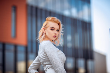 young woman in white dress posing by the building background. Beauty, fashion. Cosmetics.