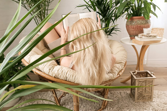 Woman reading a book, relaxing in boho room. - Powered by Adobe