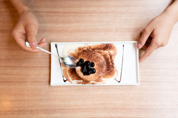 Woman having sweet food on the wooden table.