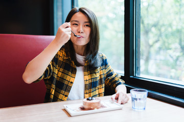 Young Asian woman enjoying delicious food in cafe.